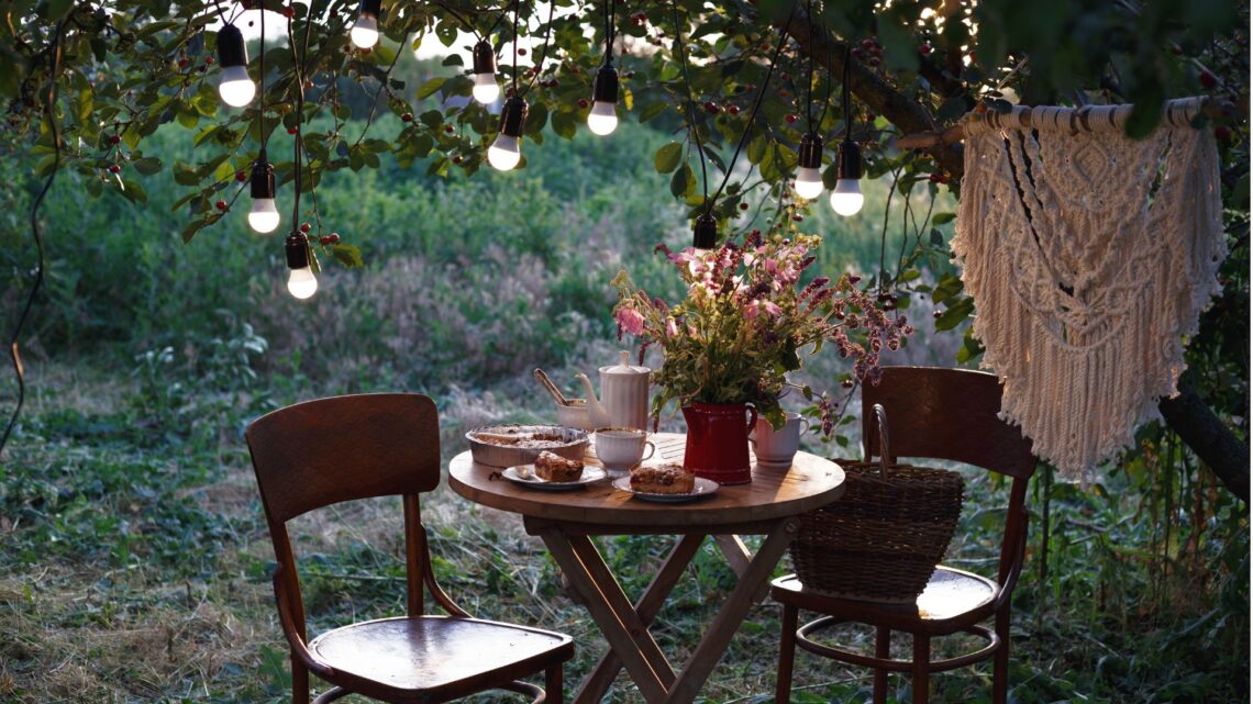 Evening in the garden, lanterns in the trees, Small table and chairs under the tree.