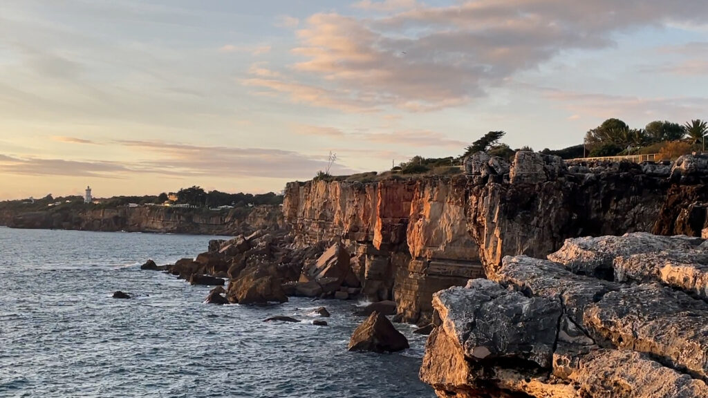 Rocky cliffs and waves hitting them in a sunset light.