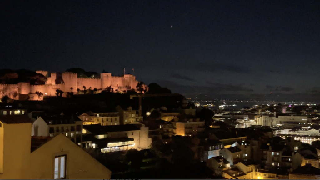 Nighttime picture from a viepoint. Big castle locating on the top of the hill on the left side of the view, citylights down in the valley on the right side of the view.